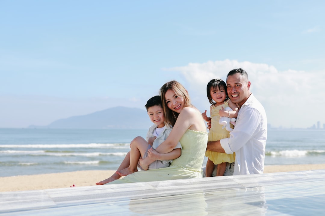 Family posing by the ocean on a sunny day