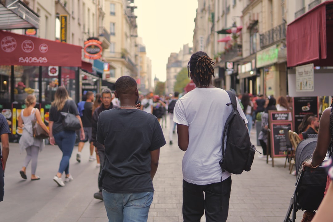 man in white t-shirt and blue denim jeans walking on street during daytime