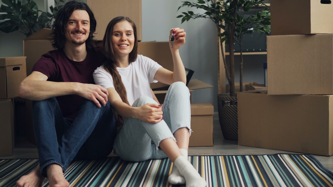 a man and a woman sitting on the floor in front of moving boxes