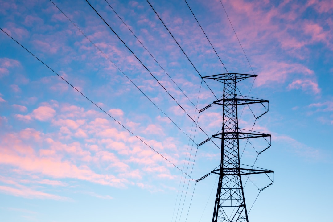 black electric pylon under orange clouds during daytime