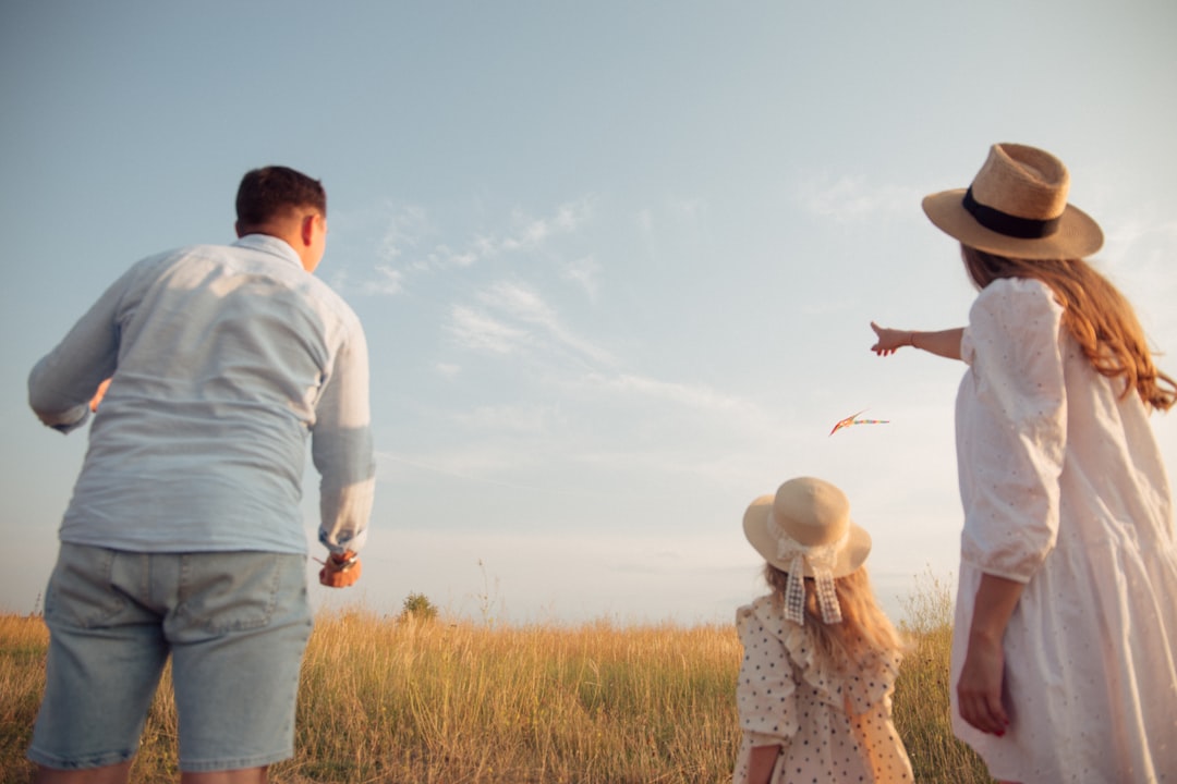 A family in a field flying a kite under a clear blue sky