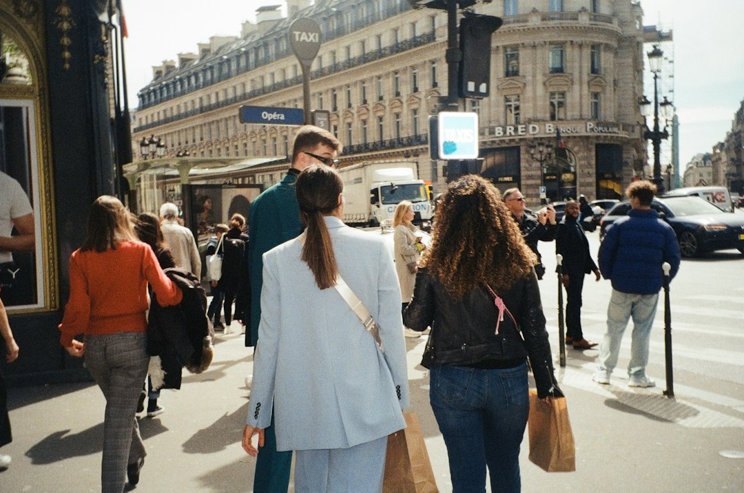 a group of people walking down a street next to tall buildings