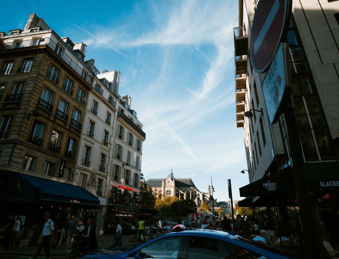 A street scene in Paris with historic buildings and a church in the distance